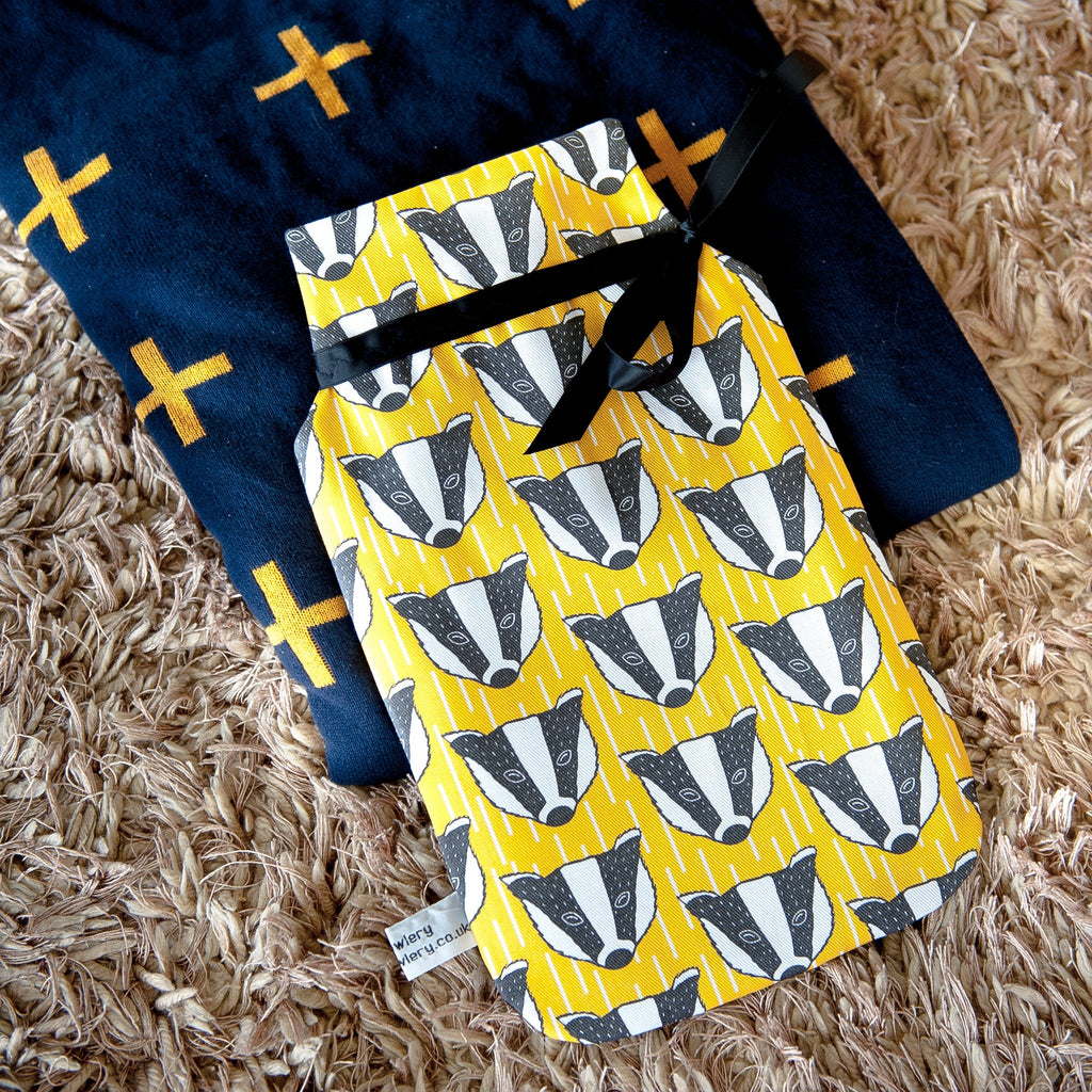 Lifestyle image showing hot water bottle.  Yellow and white fabric, geometric background with black and white badger illustration.