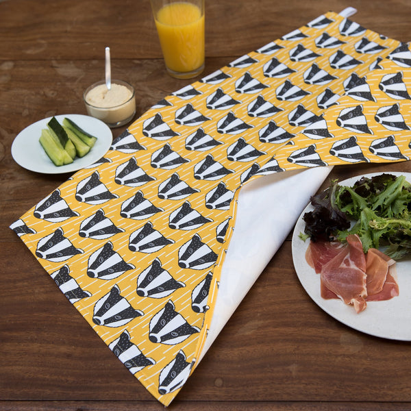 Lifestyle image with yellow and white geometric print fabric with black and white badger illustration.
