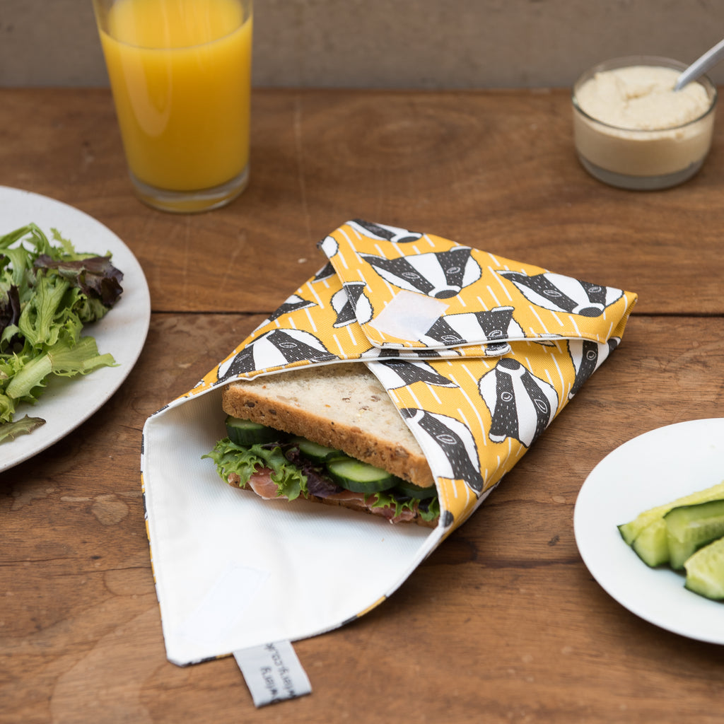 Lifestyle image showing yellow and white geometric sandwich with black and white badger illustration.