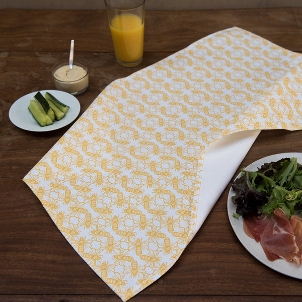 Lifestyle image. Yellow and white geometric bee motif fabric tea towel.