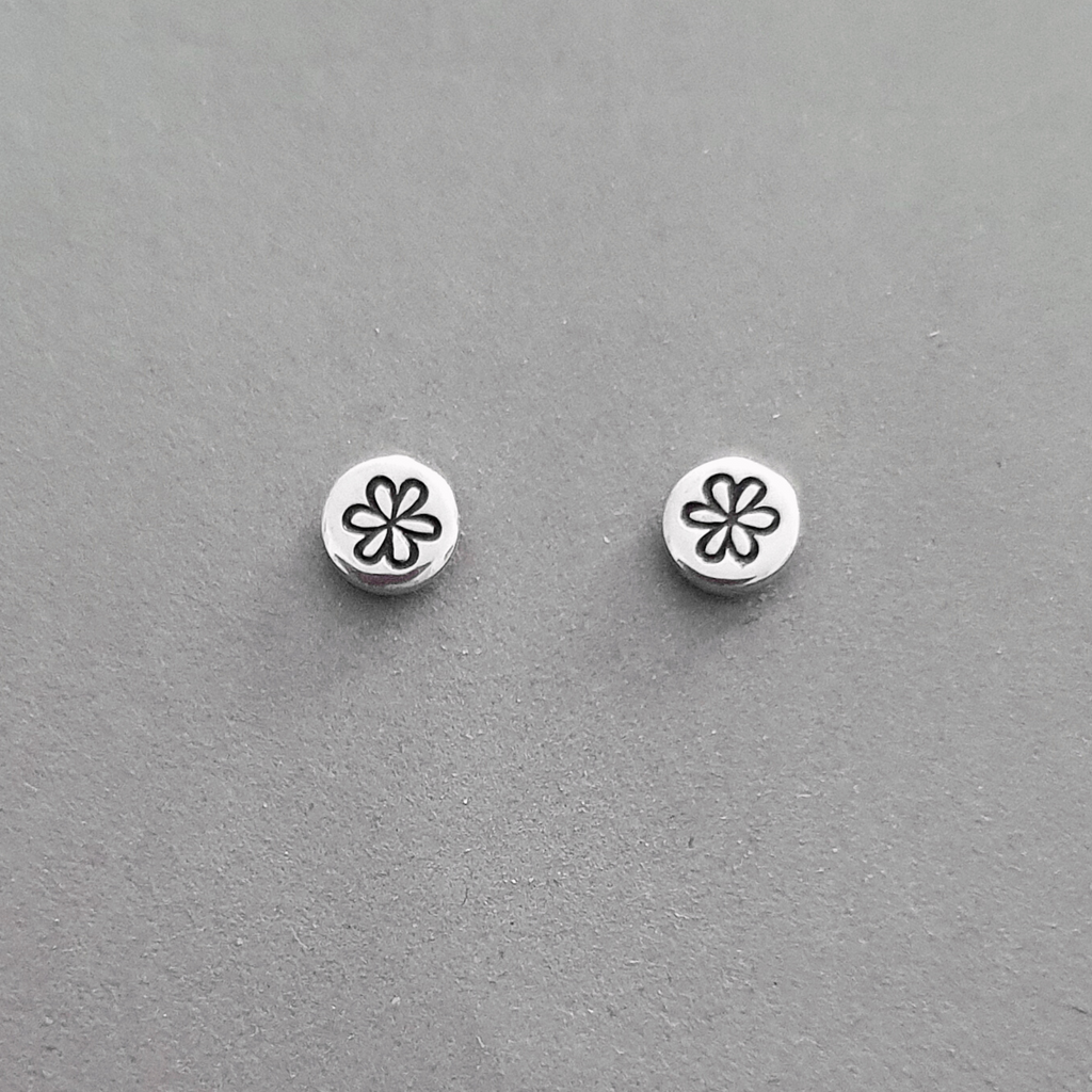 Product image. Small sterling silver stud earrings with daisy flower motif.