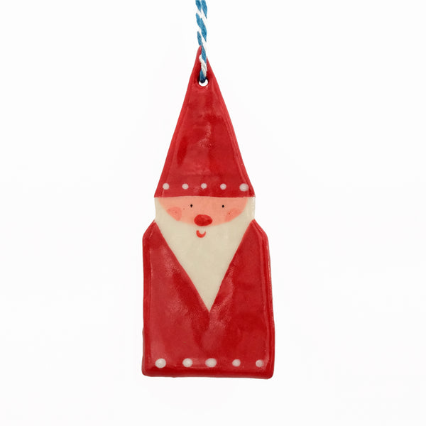 Ceramic hanging decoration. Santa wearing a pointy santa hat with white dots on the brim, and white dots along the base of his red coat. He has a long pointy white beard and rosy pink cheeks. 