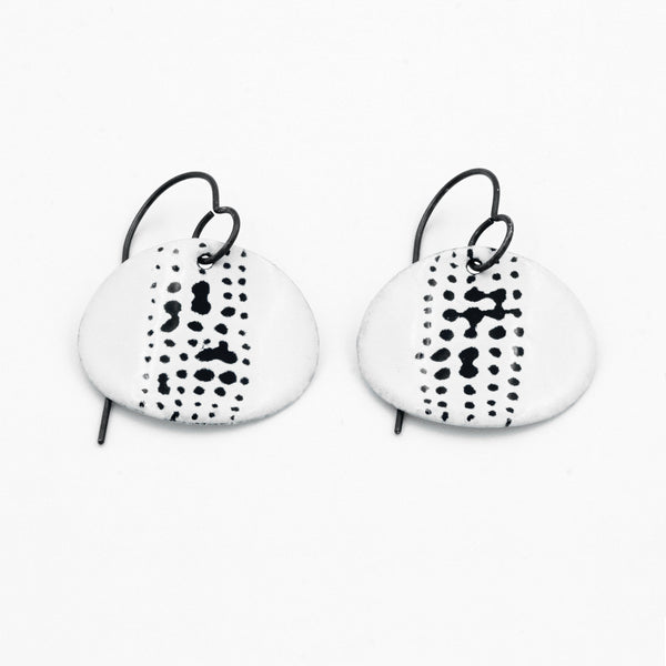White enamel oval drop earrings with mark details in black. Hoop fastening. 