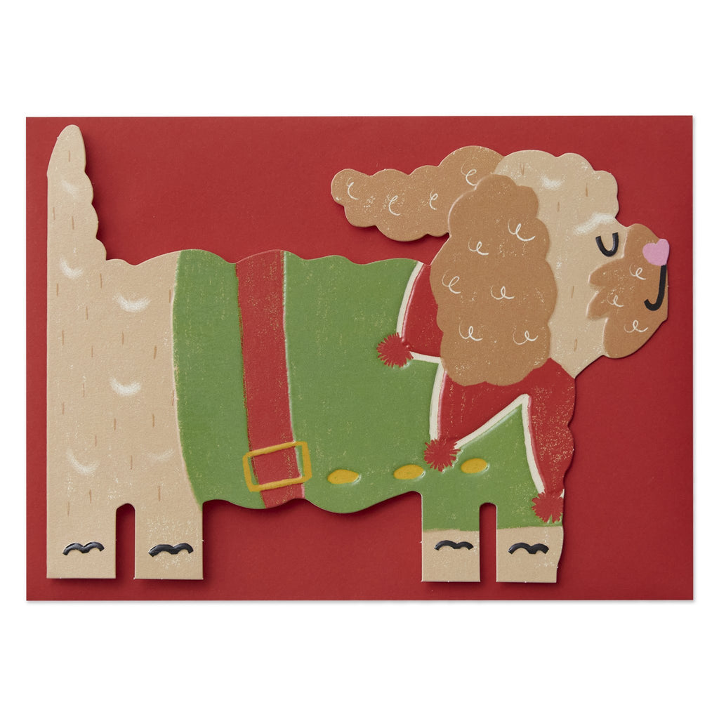 The card is die cut and embossed. The card shows an illustration of a cockapoo in side profile wearing a green and red elf costume. 