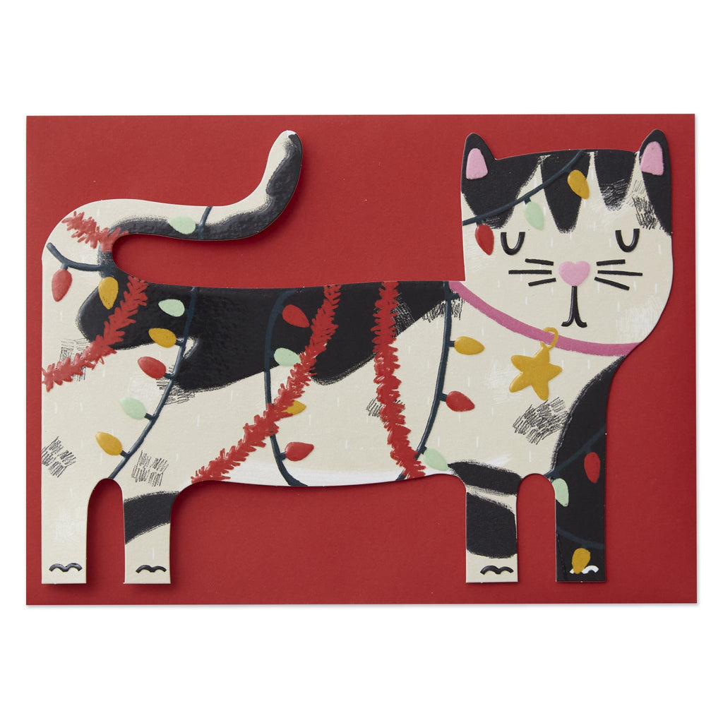 The card is die cut and embossed. The cat shows a illustration of a black and white cat in side profile, there are fairy lights and red tinsel tangled around the cat as if it has been playing with the lights. 