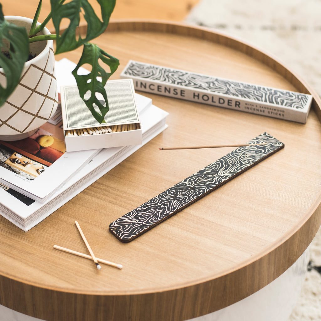 Lifestyle image. Black and white screen printed ply incense holder with 5 sandalwood incense sticks.