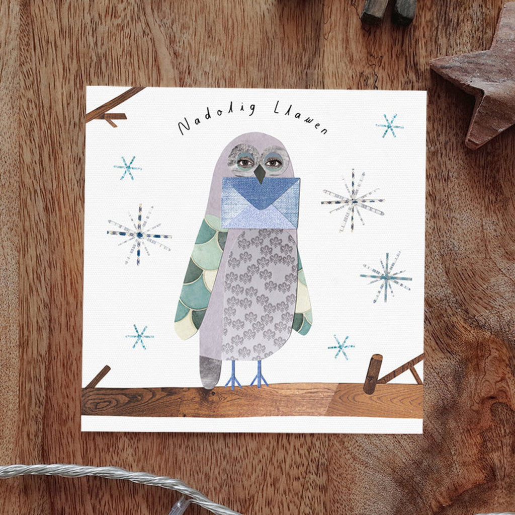 Collage style illustration on a white background with snowflakes.  In the foreground an owl sits on a branch holding an envelope in its beak. 