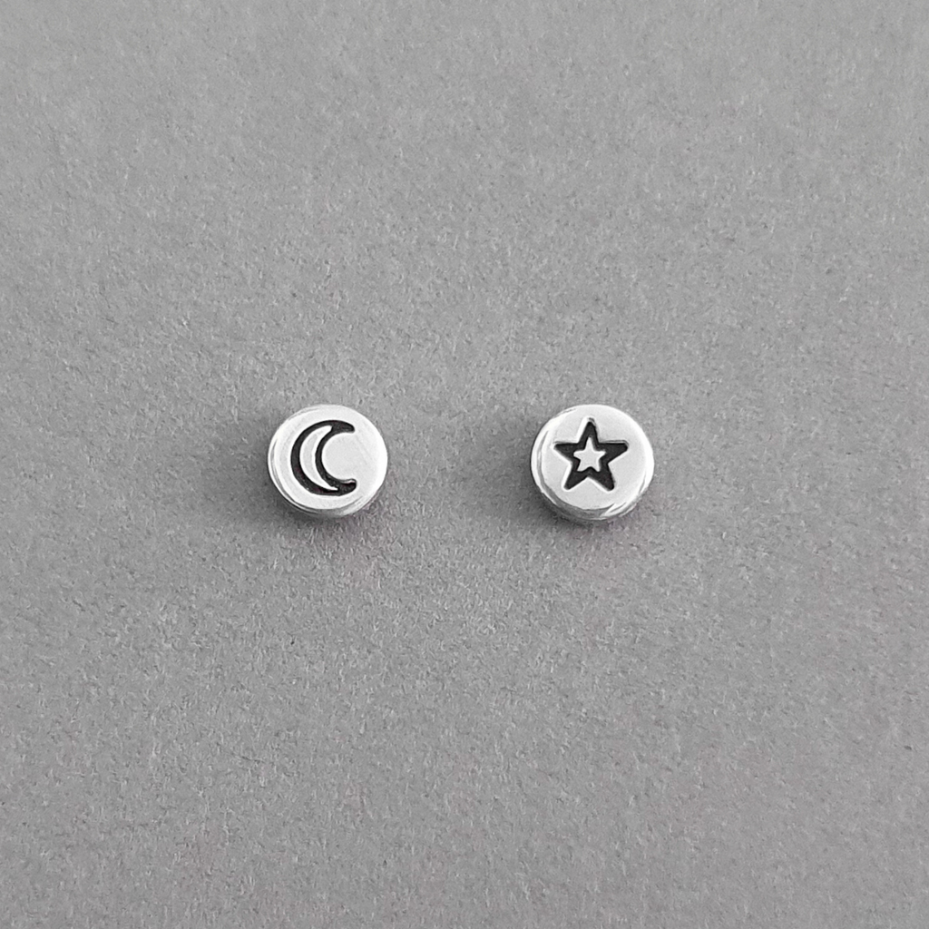 Product image on grey background. Sterling silver mismatched stud earrings. One with a crescent moon and one with a star motif. 